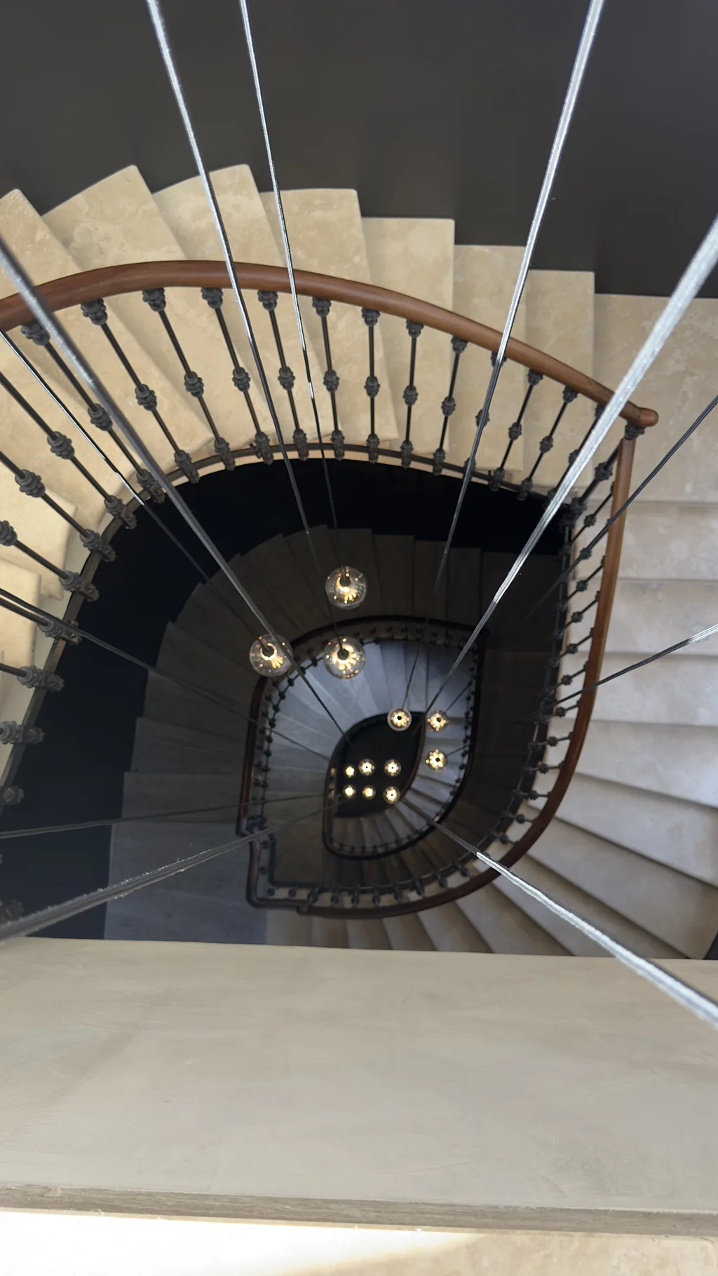 Spiral staircase beneath a cascading chandelier in an Ekinex reference villa
